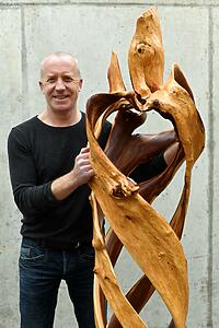 Der Künstler mit einer Baumskulptur