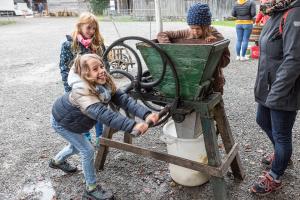 Kinder drehen an einer Mostpresse